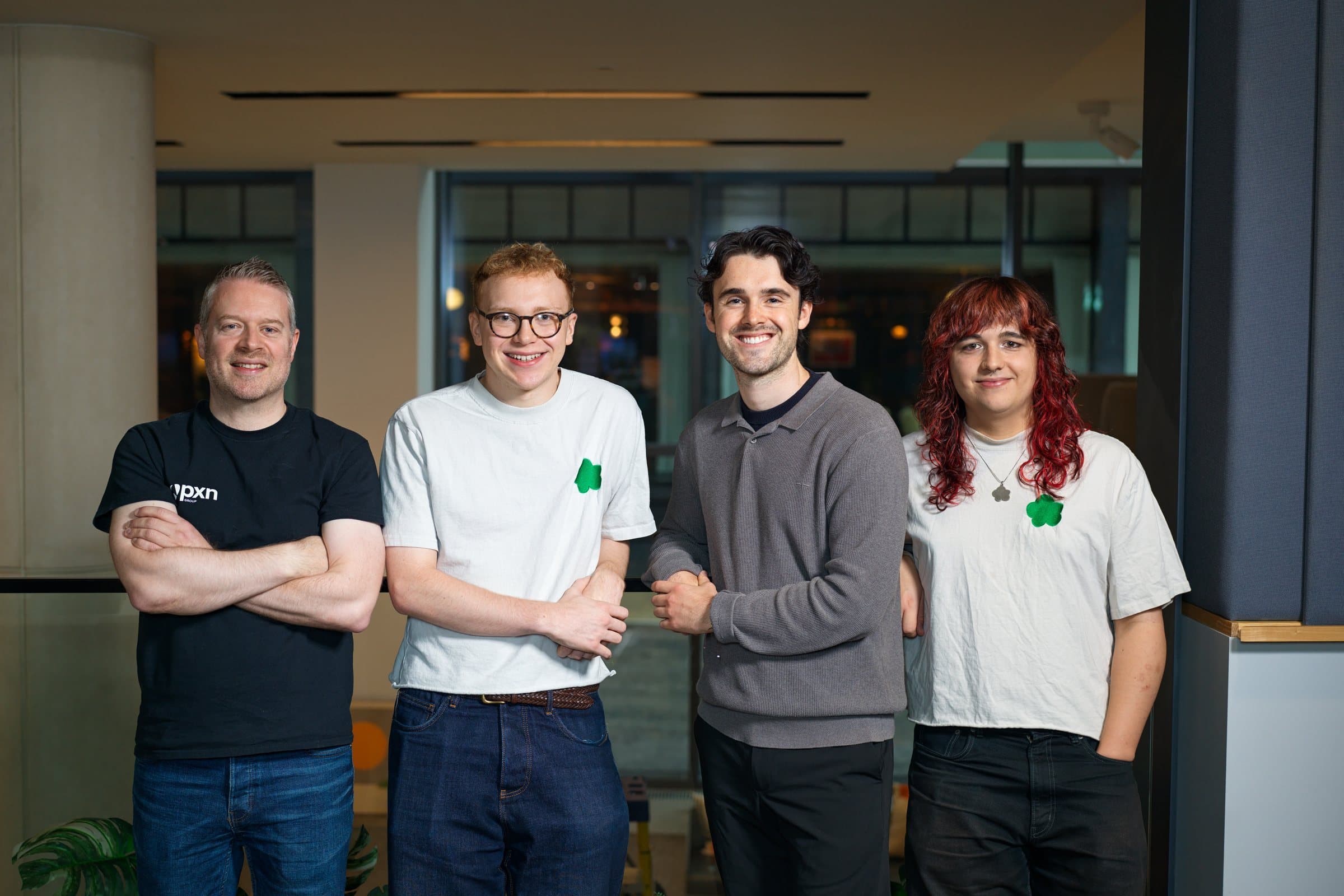Revnu with PXN Ventures: four people standing together in an office, one in a PXN t-shirt and two in white t-shirts with Revnu's green Puffy logo.